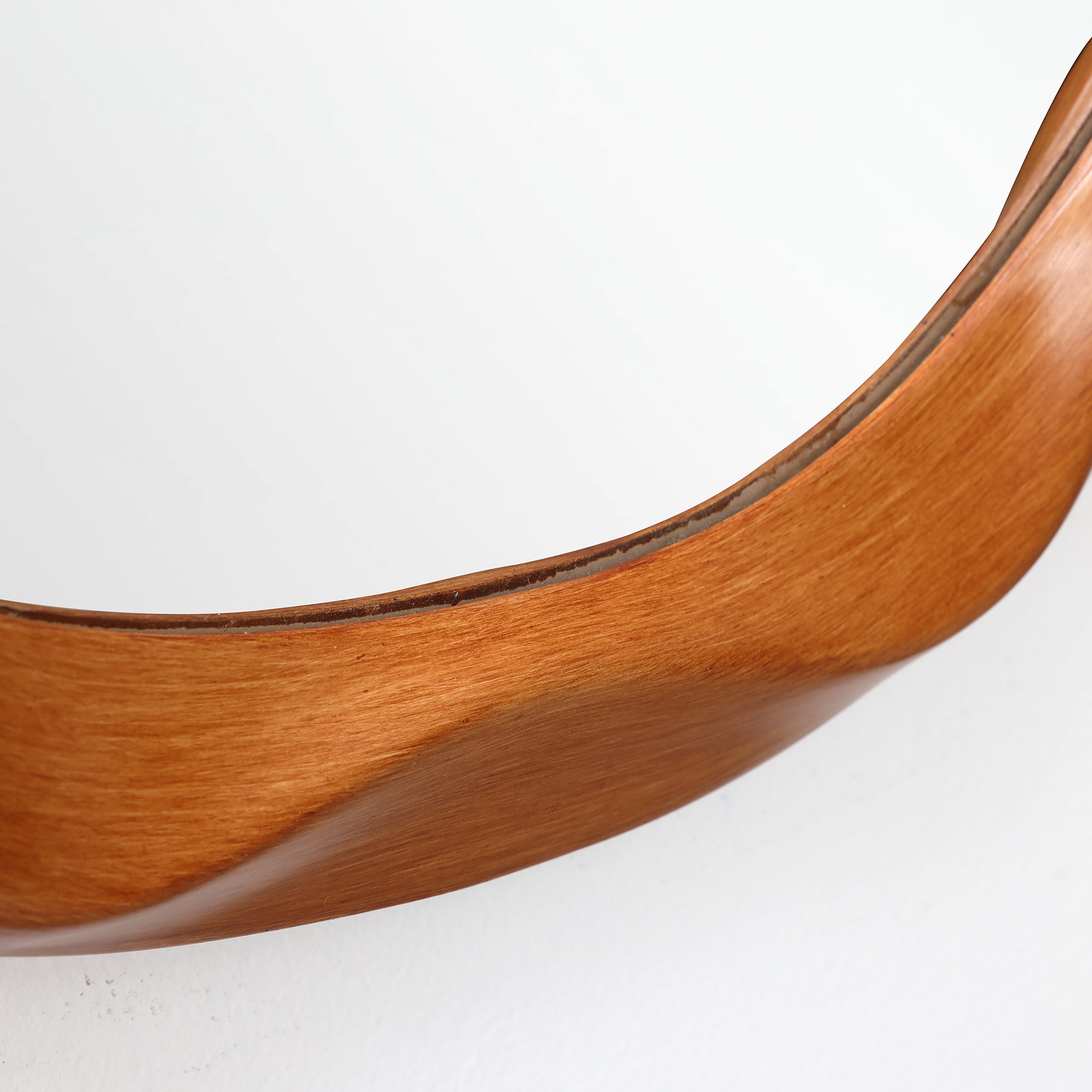 Close-up of a curved wooden frame against a white background, showing smooth grain and polished finish.