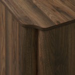 Close-up of a wood sideboard cabinet corner with a smooth, rounded edge and visible natural wood grain pattern.