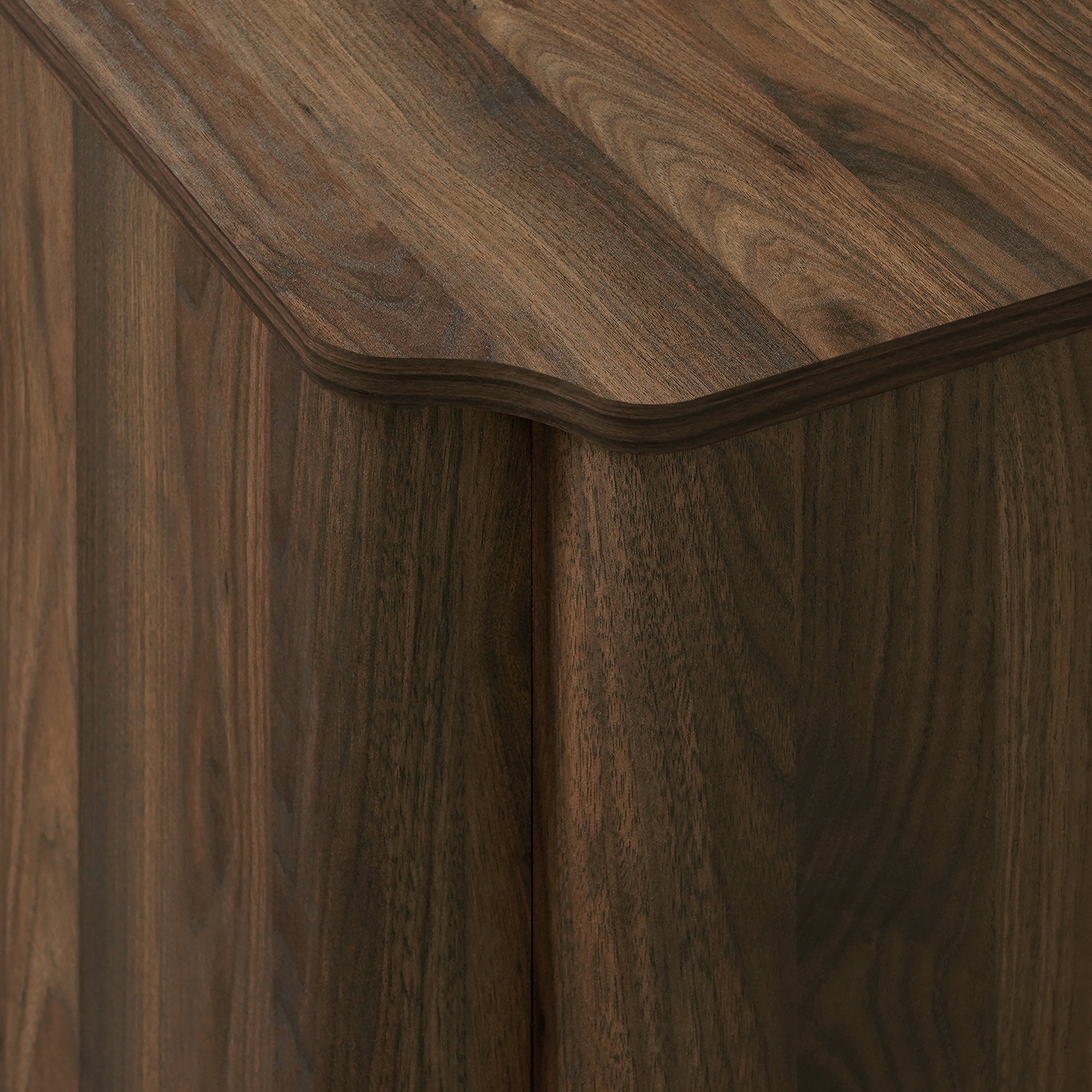 Close-up of a wood sideboard cabinet corner with a smooth, rounded edge and visible natural wood grain pattern.