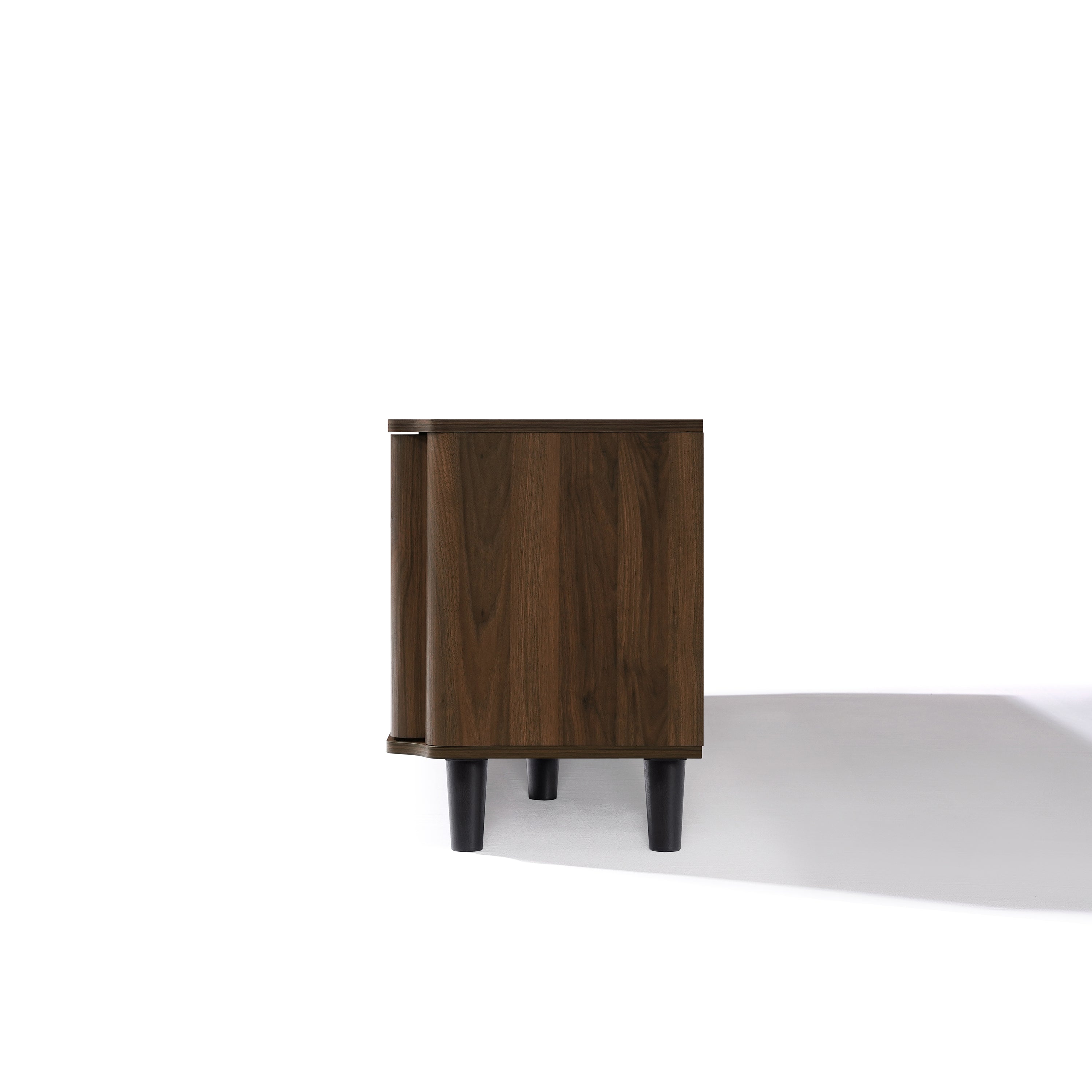 Side view of a small, rectangular mid-century modern wooden cabinet with dark legs, on a white background.