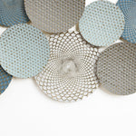 A collection of decorative round plates with intricate, textured patterns in shades of blue and gray, arranged on a white background, creates a stunning piece of abstract wall art.