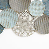 A collection of decorative round plates with intricate, textured patterns in shades of blue and gray, arranged on a white background, creates a stunning piece of abstract wall art.