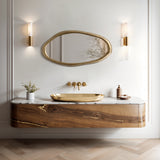 Modern bathroom with an elegant gold wall mirror, gold sink, wooden vanity, and marble countertop. Two wall sconces gracefully flank the mirror.