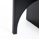 Close-up of a Bernard end/side table leg by LuxenHome, crafted from manufactured wood in black with a smooth texture and modern design against a white background. The curved cutout detail near the base adds elegance to this square side table.