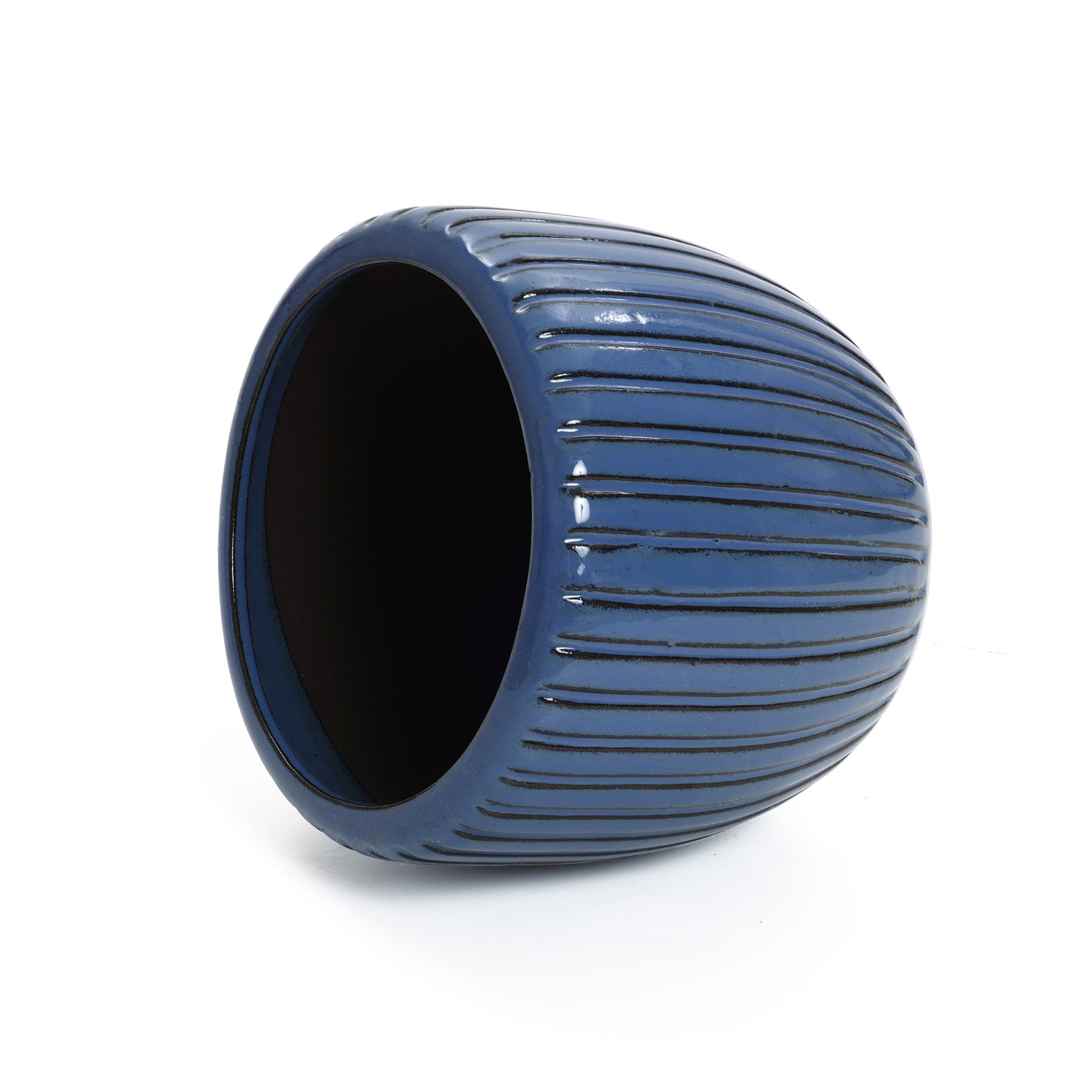 A dark blue, oval-shaped ceramic flowerpot with a three-dimensional vertical pattern lies on its side against a plain white background.