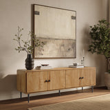 Minimalist TV stand with black legs stands against a beige wall, topped with books, candles, and a vase with branches.