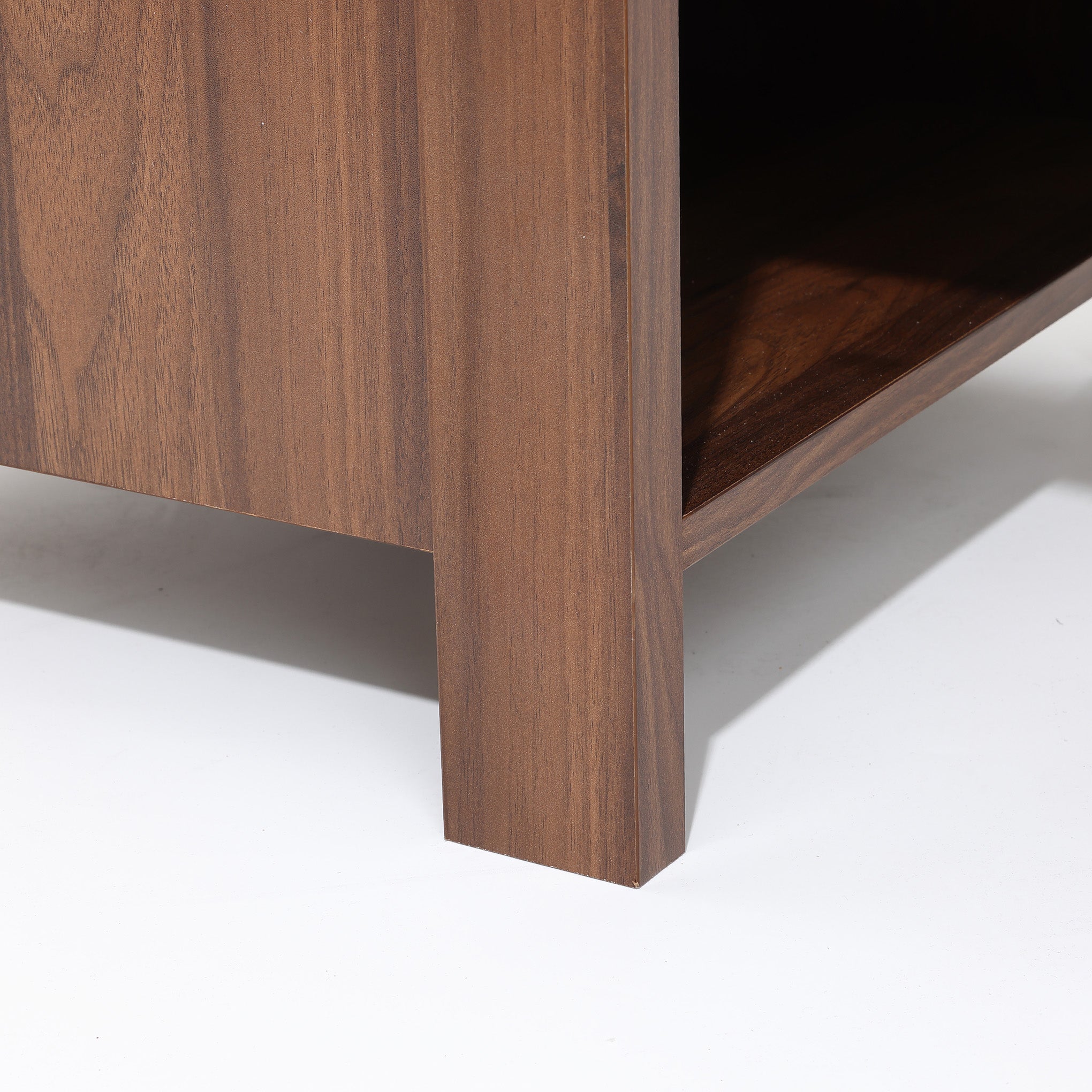 Close-up of the bottom corner of a end table nightstand with vertical legs and a textured beige side panel.