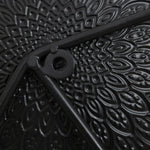 This abstract metal wall decoration showcases a close-up of a black, textured surface with a circular hole and intersecting rods. The pattern, resembling petals radiating outward, adds an artistic touch perfect for enhancing your home decor.
