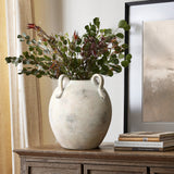 An 11 tall multi-gray and white terracotta vase with handles by LuxenHome sits on a wooden cabinet, holding lush greenery with red-tipped leaves. Stacked books are beside it, and a framed picture hangs on the wall behind.