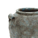 Weathered ceramic pot with a rough, textured surface and a circular handle near the rim.