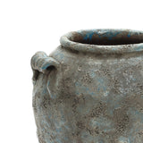 Weathered ceramic pot with a rough, textured surface and a circular handle near the rim.