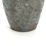 Close-up view of the lower half of a textured, gray and blue ceramic vase, an ideal accent for vintage home decor.
