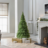 5ft artificial tree stands in living room corner, surrounded by wrapped presents, next to fireplace decor with garland.