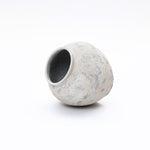 Asymmetrical modern minimalist vase with a wide opening and a textured, mottled gray and beige surface.