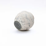 Weathered round cement flower vase lies on its side against, embodying a modern minimalist aesthetic.