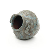 Textured weathered handcrafted vase with two small, angular handles lies on its side against a white background.