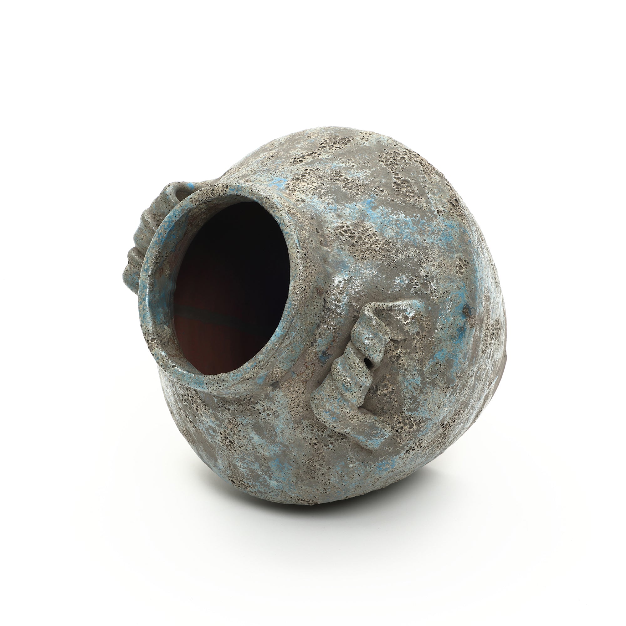 Textured weathered handcrafted vase with two small, angular handles lies on its side against a white background.