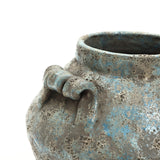 Close-up of a handcrafted vase with a rounded shape, blue and gray glaze, and a decorative handle detail near the rim.