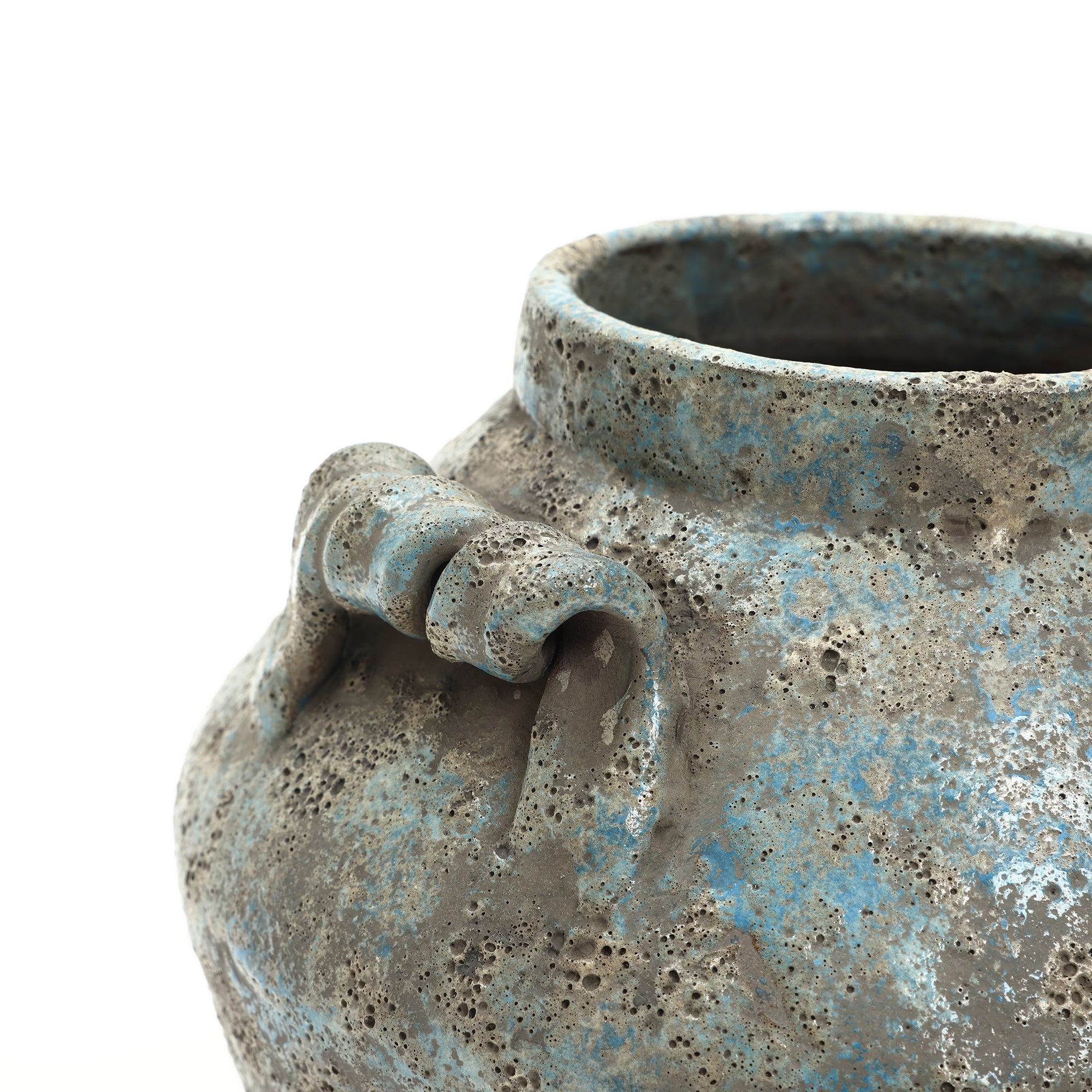 Close-up of a handcrafted vase with a rounded shape, blue and gray glaze, and a decorative handle detail near the rim.