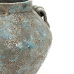 Close-up of a weathered textured ceramic vase with a rough surface, featuring blue and gray hues.