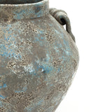 Close-up of a weathered textured ceramic vase with a rough surface, featuring blue and gray hues.