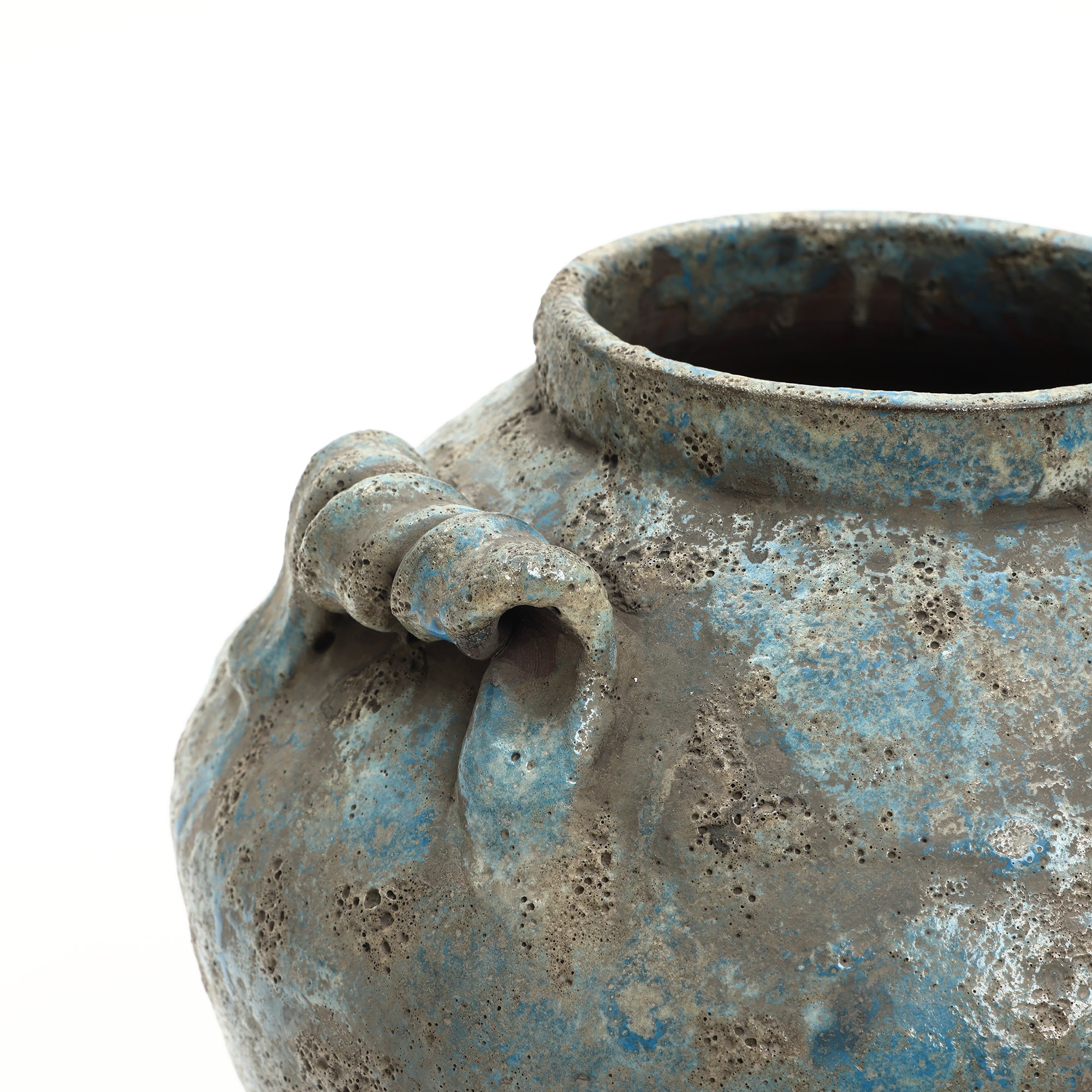 Close-up of a handcrafted pottery piece—an aged, textured ceramic pot with a blue and gray mottled surface.