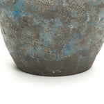 Close-up of a round ceramic vase with a mottled gray and blue surface, showcasing handcrafted pottery.