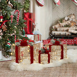 3 decor gift box with lights featuring red ribbons, led lights sit on white rug near christmas tree ,fireplace with stacked logs.