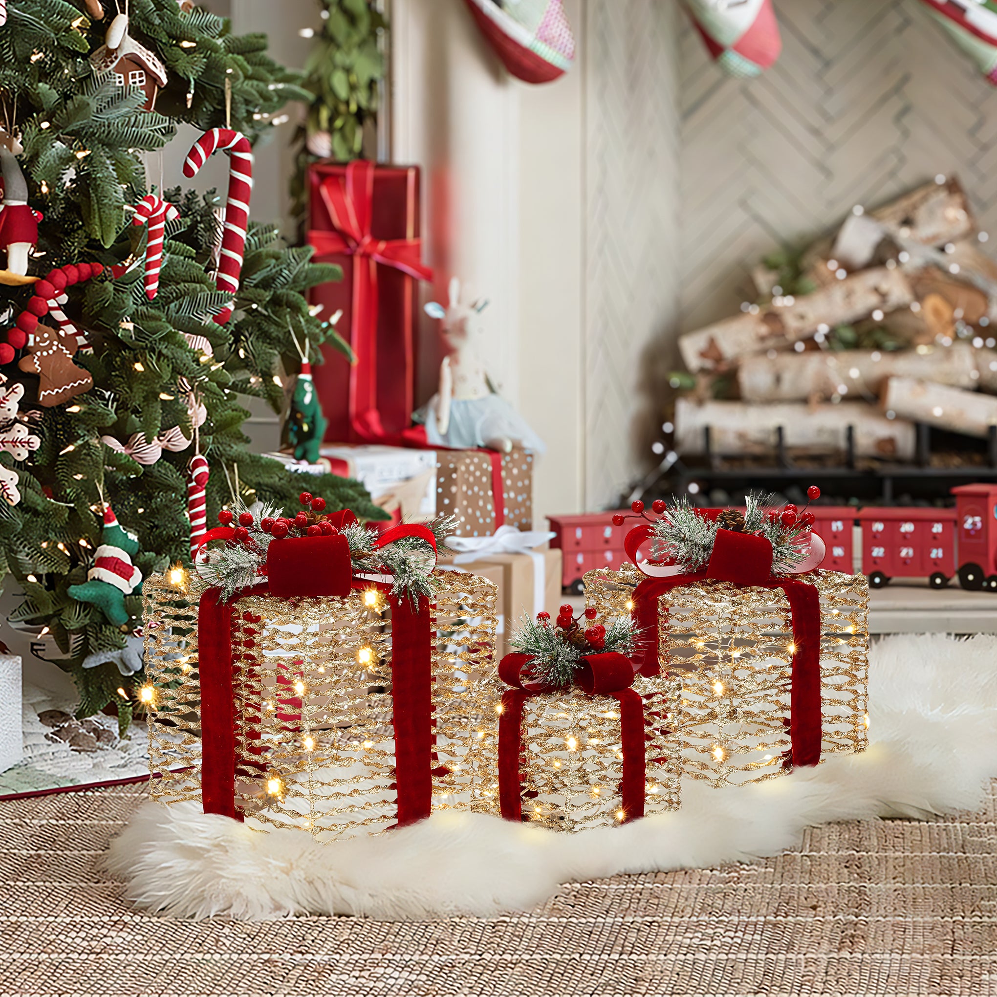 3 decor gift box with lights featuring red ribbons, led lights sit on white rug near christmas tree ,fireplace with stacked logs.