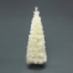 White artificial christmas tree with fluffy, feather-like branches stands on  black metal stand against plain gray background.