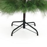 The base, lower branches of artificial christmas tree with green needles a black metal stand set against white background.