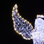 Close-up of decor wire angel wing outlined with white,yellow outdoor holiday lights against black background.