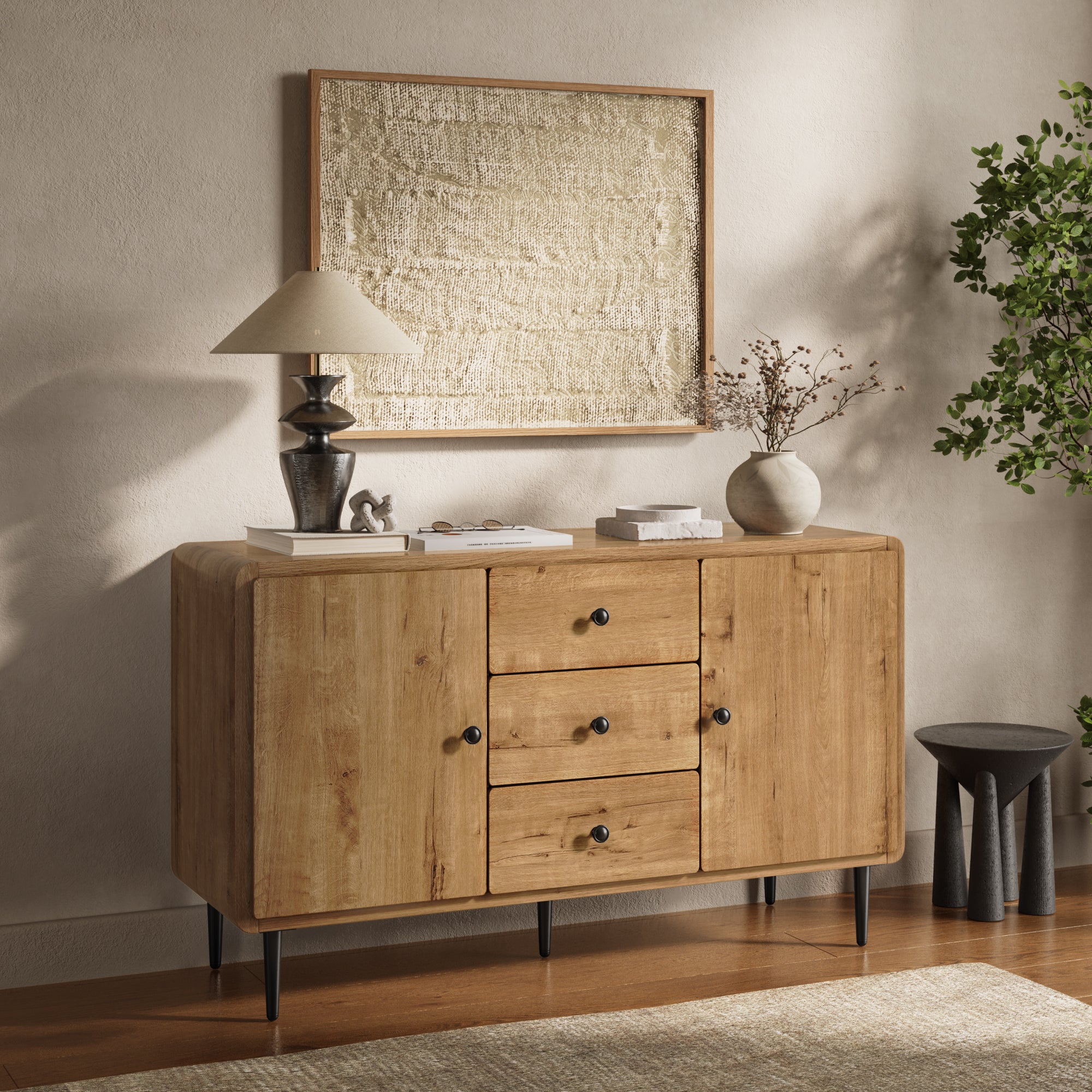 Wood buffet cabinet with three drawers and two cabinets, stands beneath a textured framed artwork.