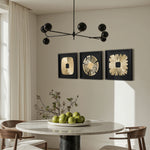 Sits under a black chandelier and three gold abstract metal wall art pieces, creating striking modern wall decor.