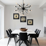 Modern dining room with a white square table, abstract metal wall art, and a black sputnik chandelier.