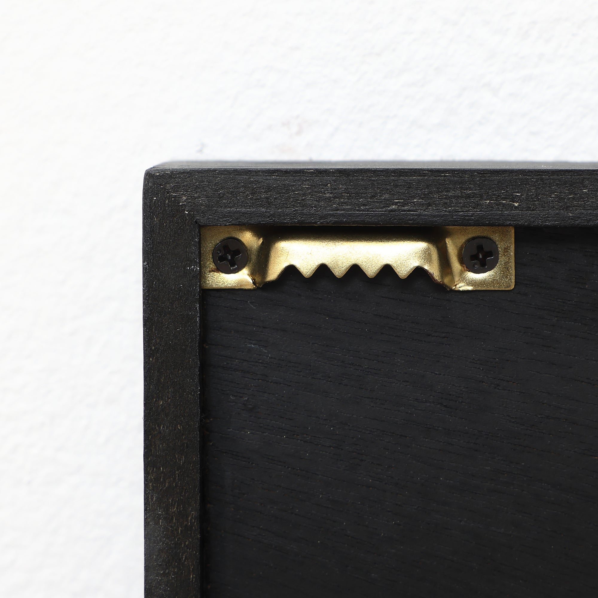 Hanger attached to the back of a black wooden frame with two screws, ideal for securely displaying abstract metal wall art or modern wall decor.