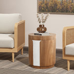Round wood side table with elegance stands between two armchairs, holding a brown vase with flowers and a closed book.
