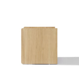 Square light oak wood nightstand with smooth surfaces and rounded corners.