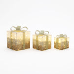 3 illuminated gift boxes with gold glitter, bows are arranged in row from largest to smallest on white background.