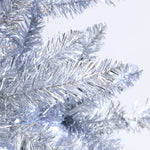 Close-up of artificial silver tinsel branches from Silver Christmas Tree, resembling a pine tree, with plain light background.