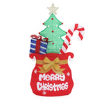 Red sack with Merry Christmas, holds green Christmas tree, blue gift box with red bow, large red-white candy cane.