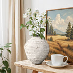 Textured cement vase with white flowers sits on a wooden table beside, creating a calming home décor scene.