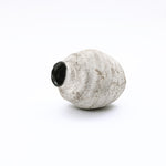 Irregularly cement vase with a rough, grayish-white surface and a glossy black opening.