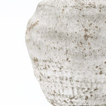 Close-up of a cement vase with a weathered speckled surface, adding modern flair to your home décor.