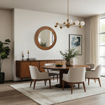 Modern dining room with a wooden table, white chairs, sideboard, oak wood frame round wall mirror, and a gold chandelier.