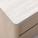 Close-up of a light wood cabinet with a textured, stone-like surface and two visible drawer fronts.