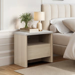 Modern end table with a drawer, open shelf holds a lamp, books, greenery in a vase, and a decorative sphere.