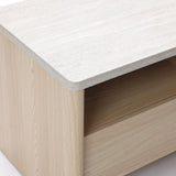 Close-up of a modern end table featuring a light-colored, stone-like surface top and a single drawer.