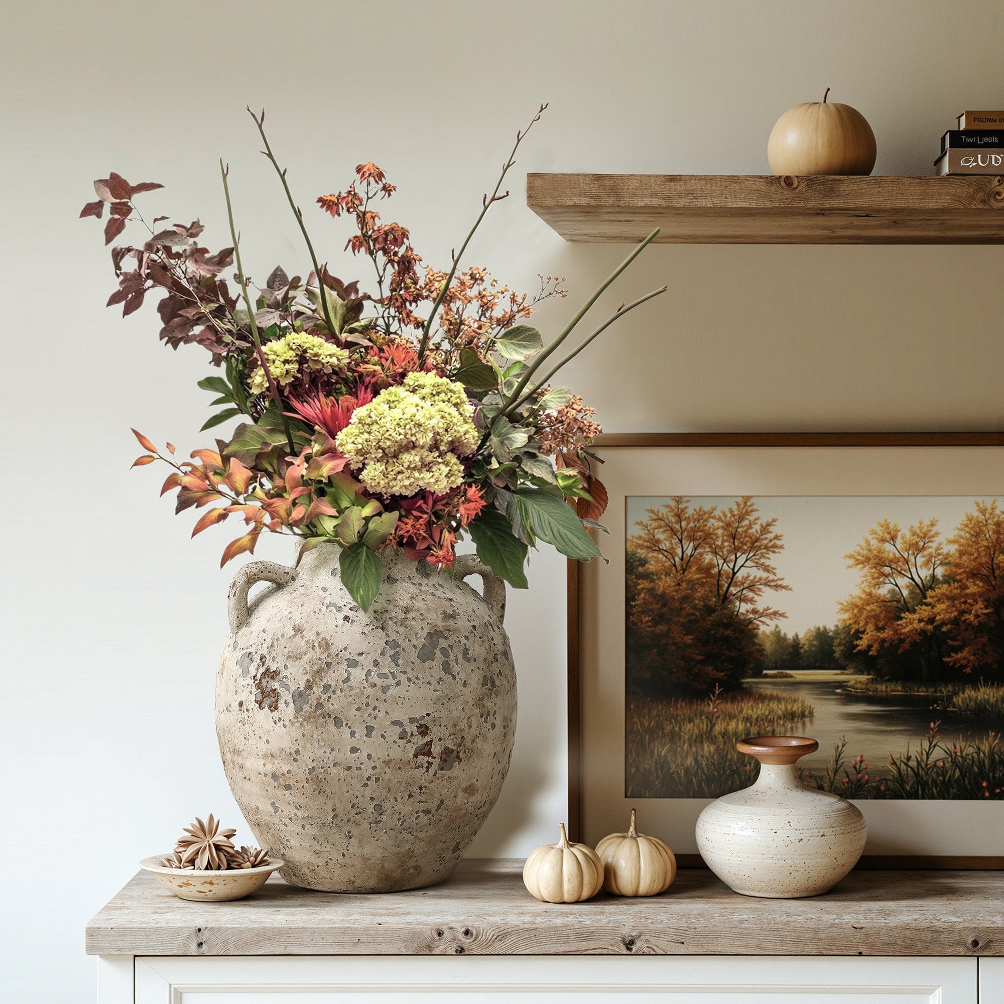 A large Terracotta Vase with autumn foliage sits on the floor next to a cream-colored sofa with patterned pillows in a cozy farmhouse living room.