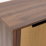A close-up of a wood storage cabinet with a smooth finish and a woven beige basket partially visible in one of its compartments.